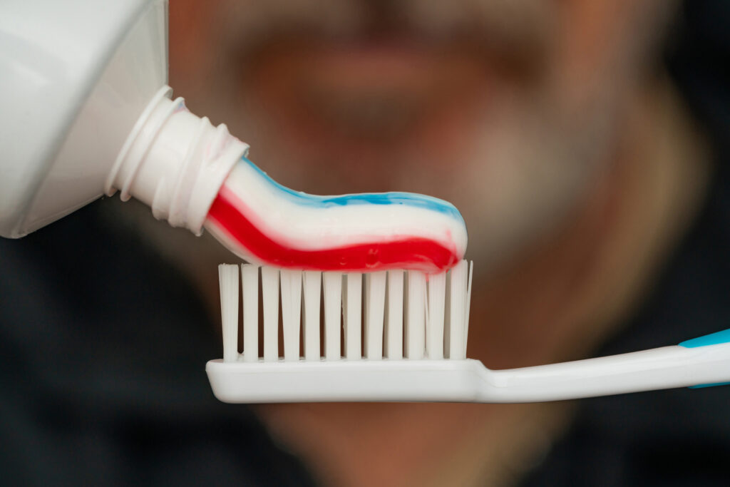 Squeezing colored toothpaste onto a toothbrush.